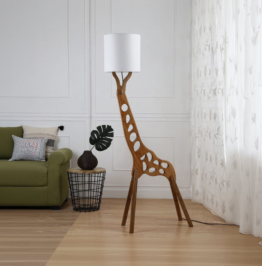 Wooden giraffe-shaped floor lamp with a white lampshade in a room setting.