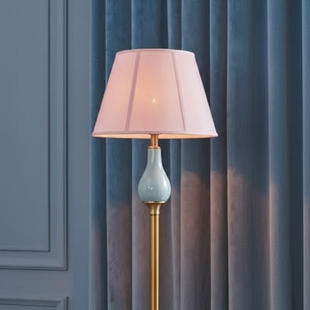 Floor lamp with a pink shade and gold base against a blue curtain background