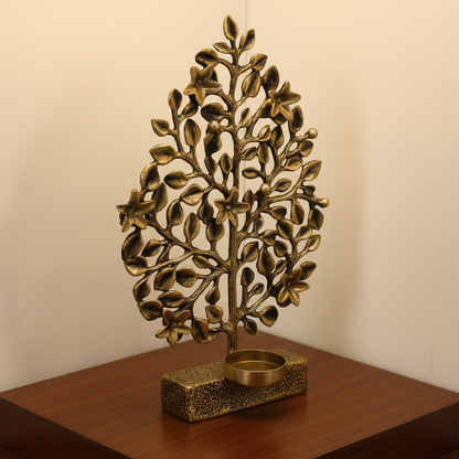 Bronze tree-shaped candle holder on a wooden surface with a plain background