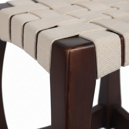 Close-up of a stool with woven seat and dark wooden legs on a white background