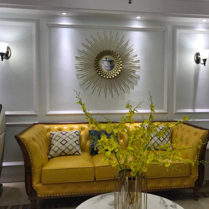 Yellow sofa with decorative pillows and a vase of yellow flowers in a room with wall art.
