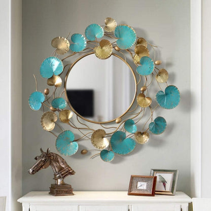 Decorative wall mirror with turquoise and gold leaf design on a gray wall.