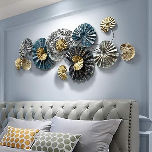 Decorative wall art with circular metal pieces in gold, silver, and blue above a bed with patterned pillows.