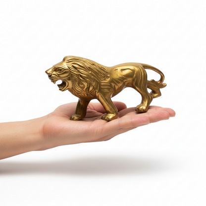 Gold lion figurine held in a hand against a white background