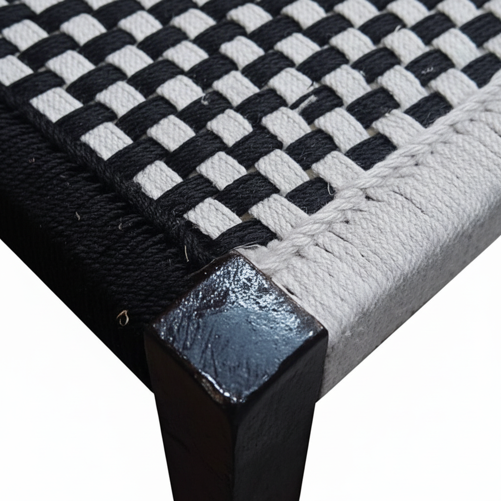 Close-up of a woven black and white mat with a metallic corner piece on a white background