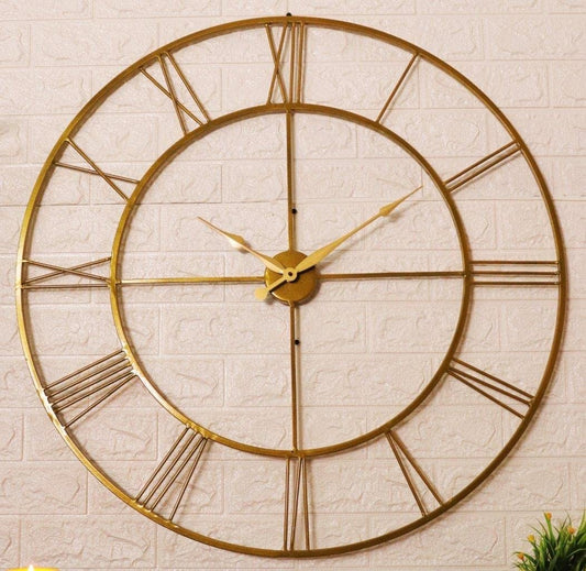 Gold wall clock with Roman numerals on a textured beige wall.