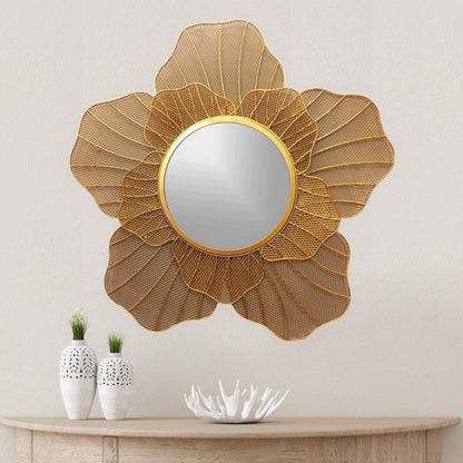 Decorative gold mirror with a floral design on a wall above a wooden console table.