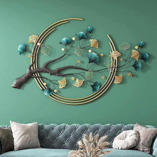 Decorative wall art with branches and leaves on a green wall above a sofa.