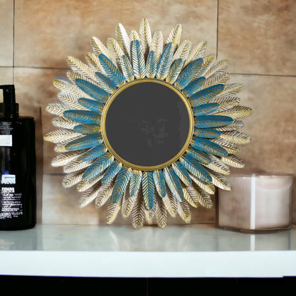 Decorative wall mirror with feather design on a shelf against a beige wall.