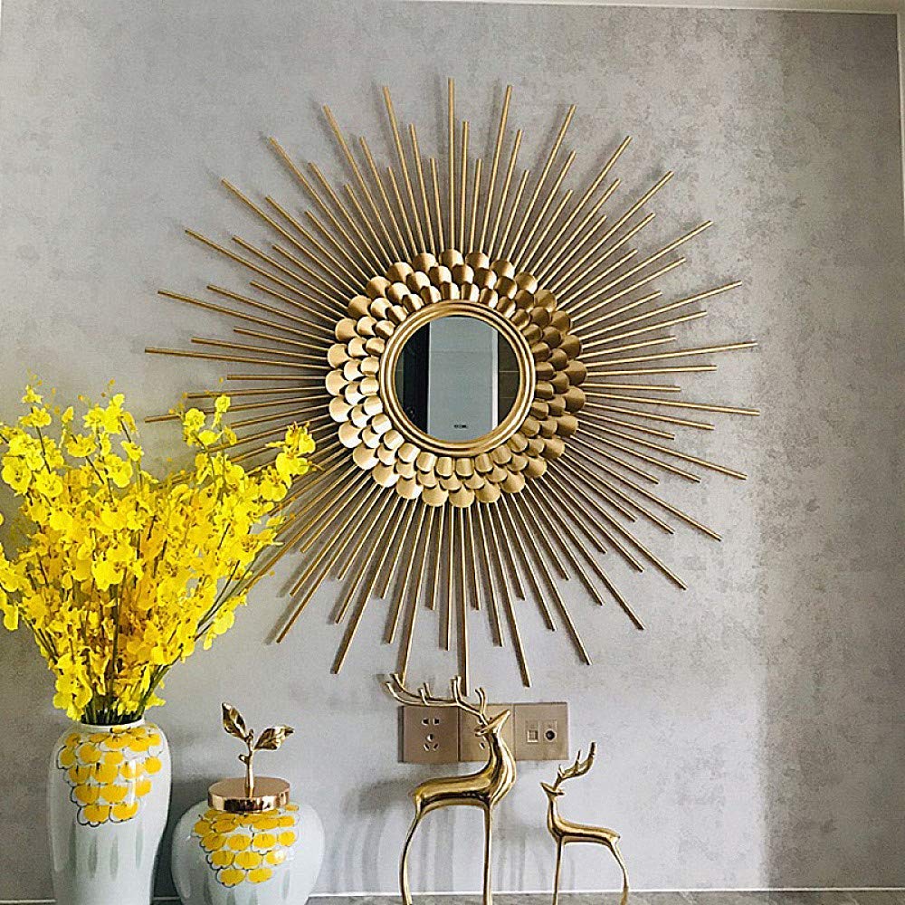 Decorative gold sunburst mirror on a wall with yellow flowers and decorative deer statues.
