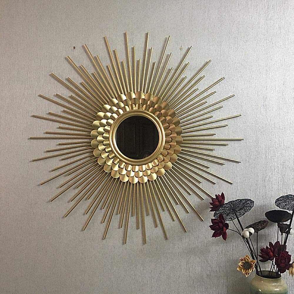 Decorative gold sunburst mirror on a wall with a vase of flowers in the corner.