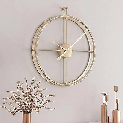 Gold wall clock on a light gray wall with decorative elements.