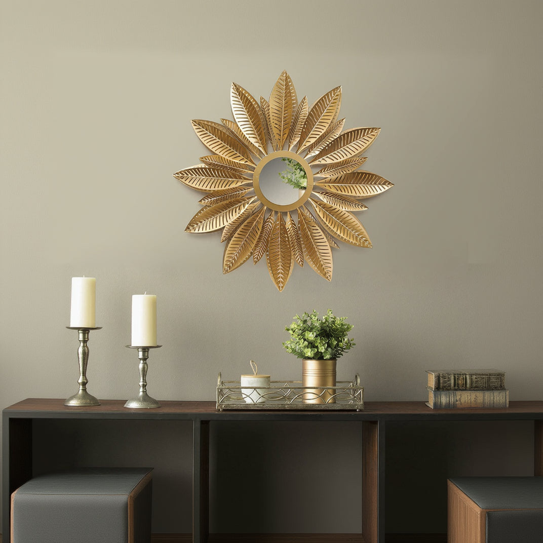 Decorative sunflower-shaped mirror on a wall above a wooden console table with candles and a plant.