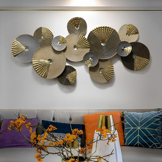 Decorative wall art with circular metal plates on a white wall above a sofa with colorful pillows.