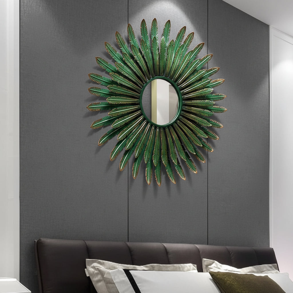 Decorative wall mirror with green leaf-like design on a gray wall above a bed.