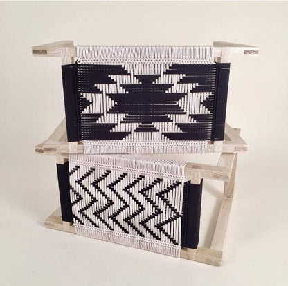 Woven basket with geometric patterns on a wooden stand against a white background