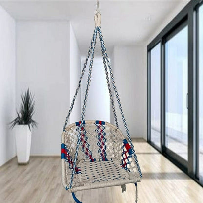 Woven chair swing with colorful pattern hanging in a room with a sliding glass door.