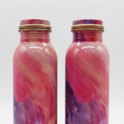 Two marbled pink and purple bottles with gold caps on a white background