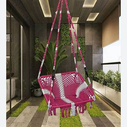 Pink and white hanging chair in a modern indoor setting with plants and a glass wall.