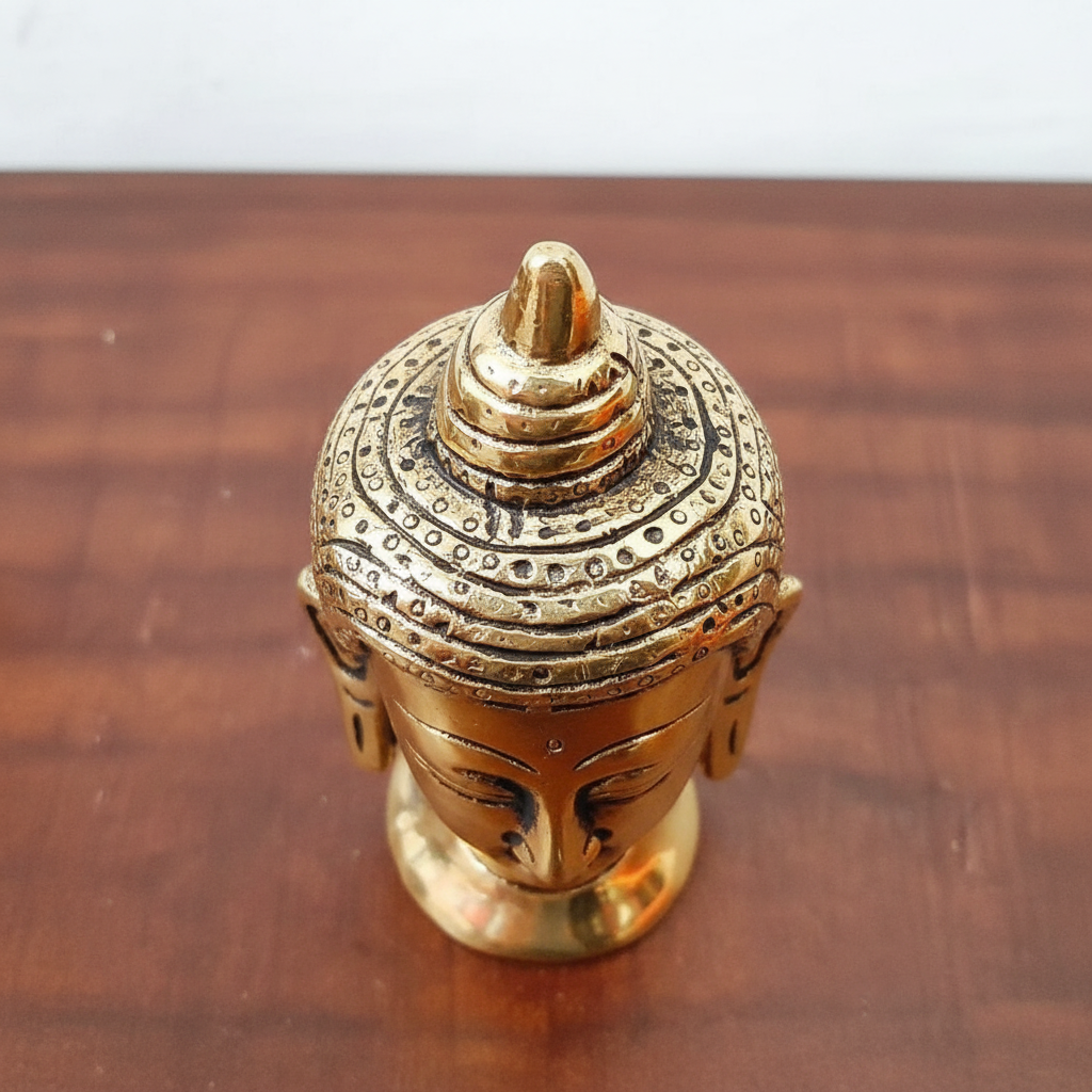 Bronze Buddha head figurine on a wooden surface