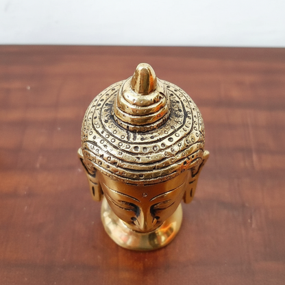 Bronze Buddha head figurine on a wooden surface
