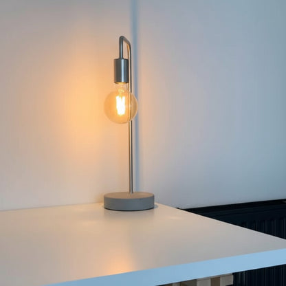 Modern table lamp with a concrete base and metal shade on a white surface.