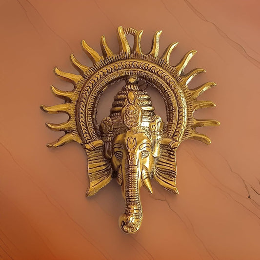 Decorative wall art of a gold elephant head with sun design on an orange background