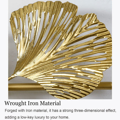 Gold leaf-shaped wall decor with text describing wrought iron material.