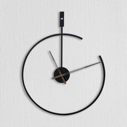 Modern wall clock with black frame and silver hands on a light gray background