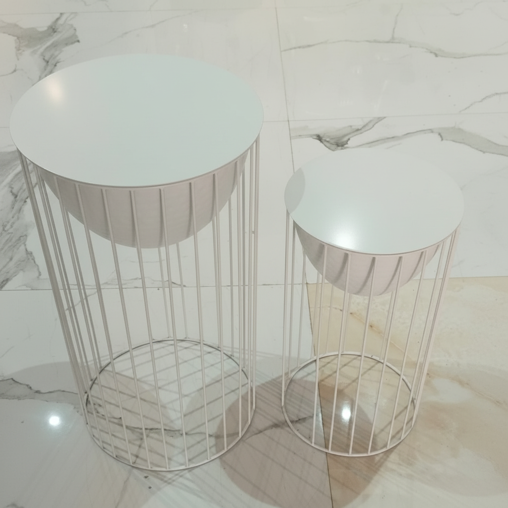 Two small round tables with white tops and metal bases on a marble floor.