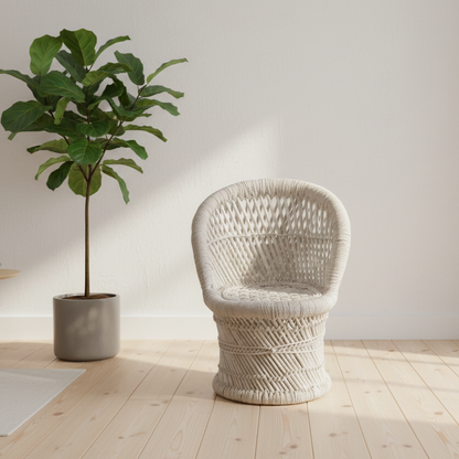 Wicker chair next to a potted plant on a wooden floor with a white wall background