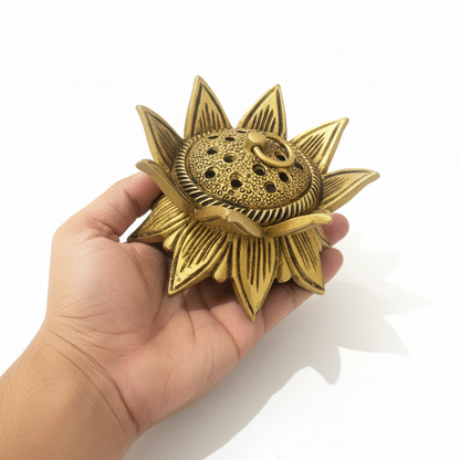 Hand holding a gold sunflower-shaped object against a white background