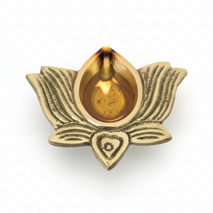 Brass lotus-shaped oil lamp with a lit wick on a white background