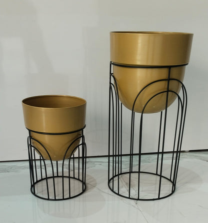 Two gold planters with black wire stands on a light gray background