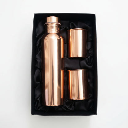 Rose gold water bottle and cup set in a black box on a light gray background