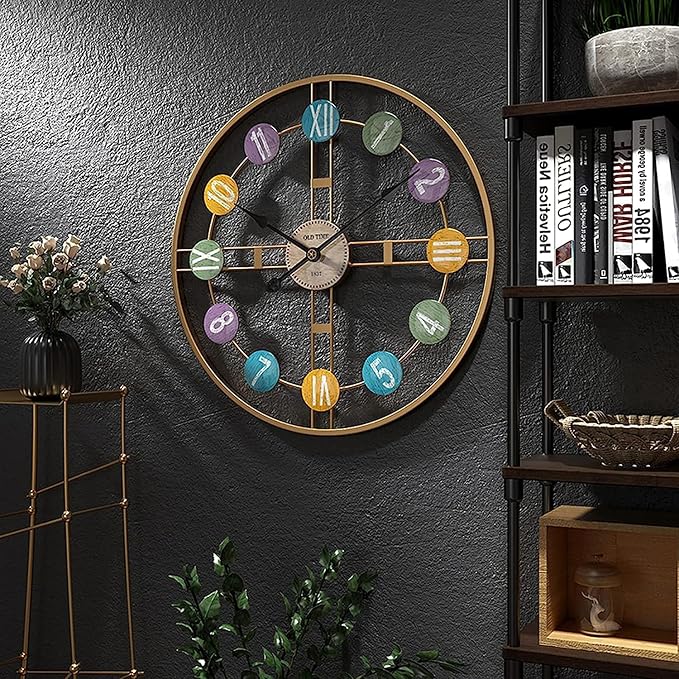 Decorative wall clock with colorful numbers on a dark gray wall, next to a bookshelf and small plant.