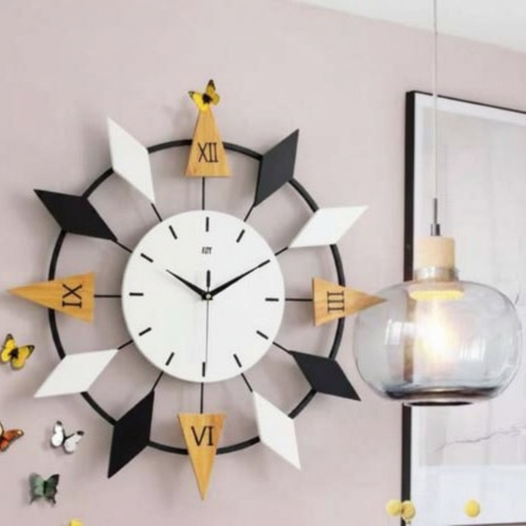 Decorative wall clock with black, white, and yellow design on a light pink wall.