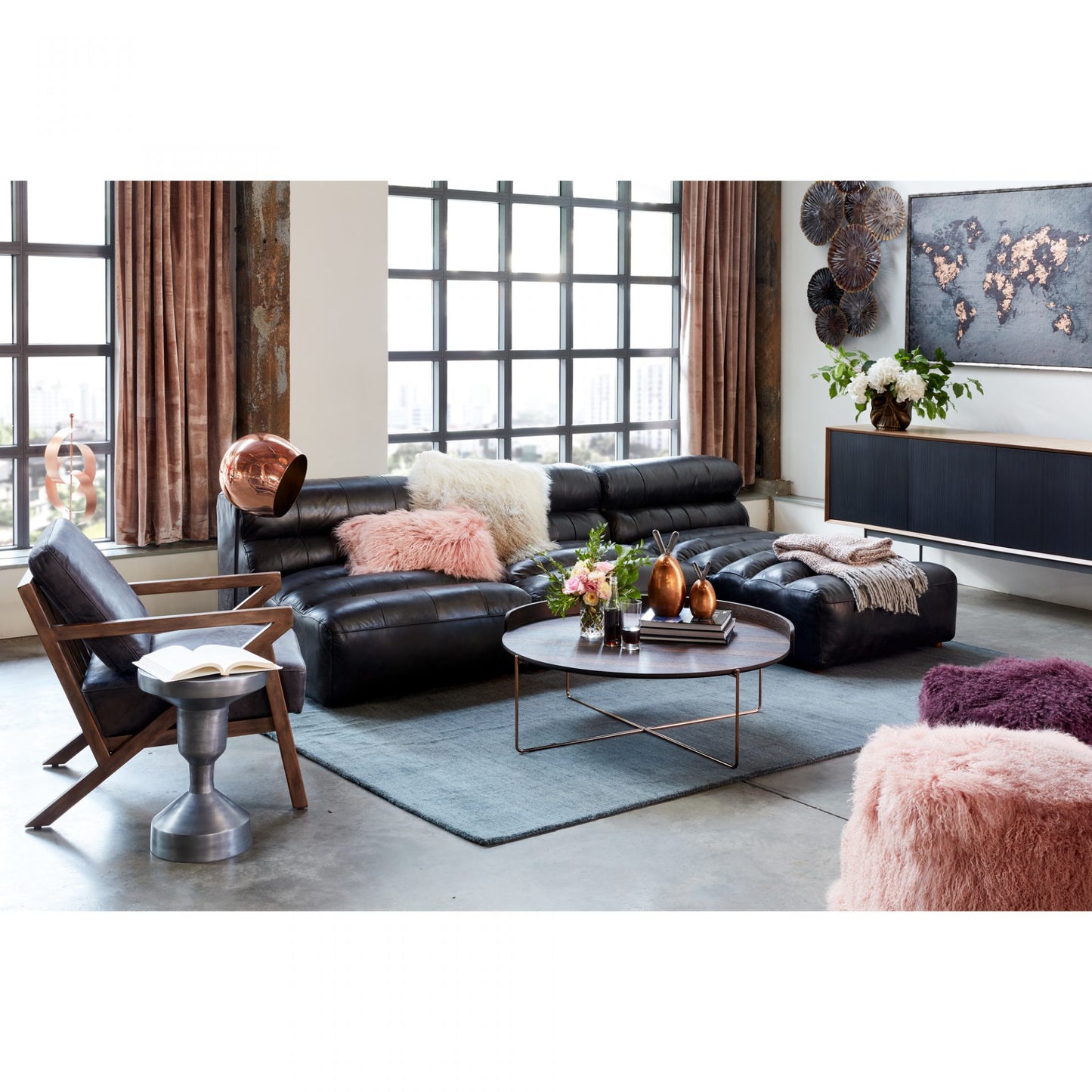 Modern living room with black leather sofa, armchair, and decorative elements.