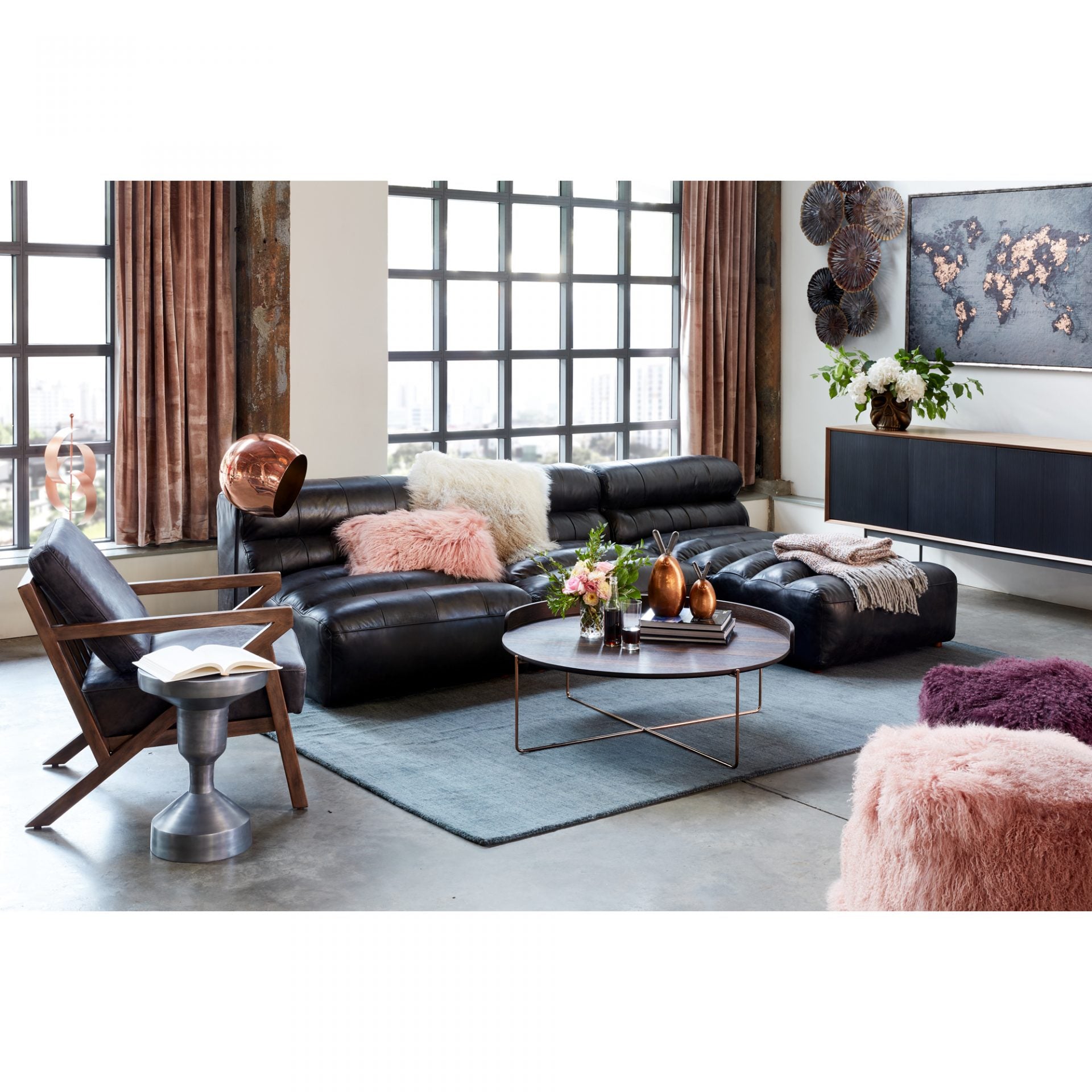 Modern living room with black leather sofa, armchair, and decorative elements.