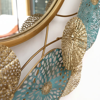Decorative wall mirror with gold frame and intricate designs on a white wall.