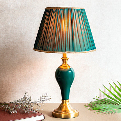 Table lamp with green and gold shade on a neutral background