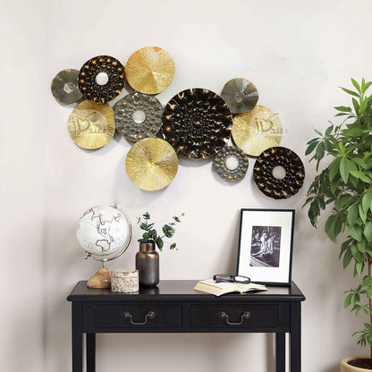 Decorative wall art with circular metal plates on a white wall above a black cabinet.