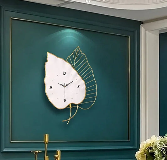 Decorative wall clock with leaf design on a teal wall