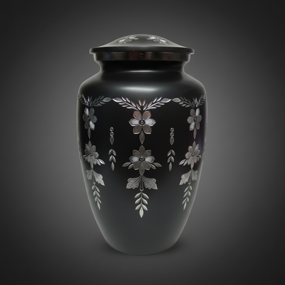Black urn with silver floral patterns on a dark background