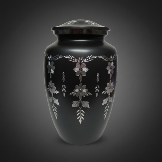 Black urn with silver floral patterns on a dark background