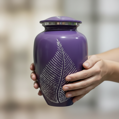 Purple urn with a white leaf design held by a hand against a blurred background