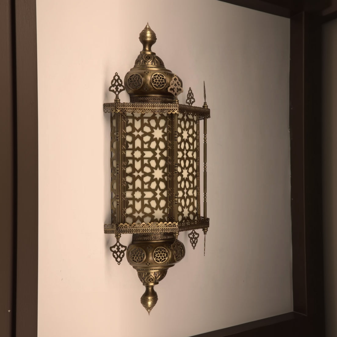 Decorative brass lantern with intricate patterns on a plain background