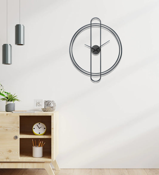 Modern wall clock on a white wall with a wooden cabinet and decorative items.