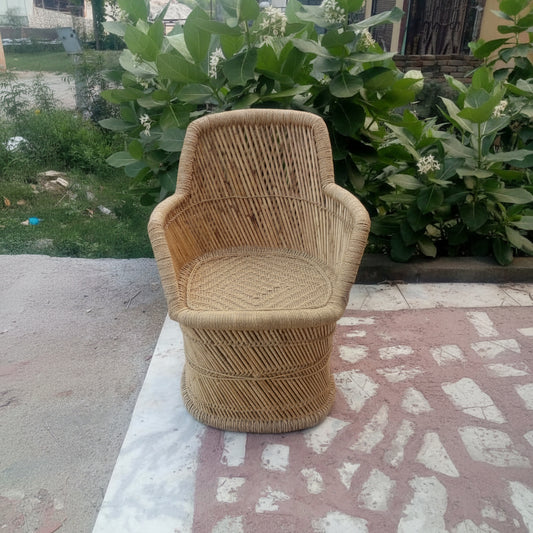 Wicker chair on a stone patio with greenery in the background